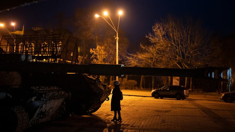 A woman stands in front of a display of destroyed Russian tanks and armoured vehicles in...